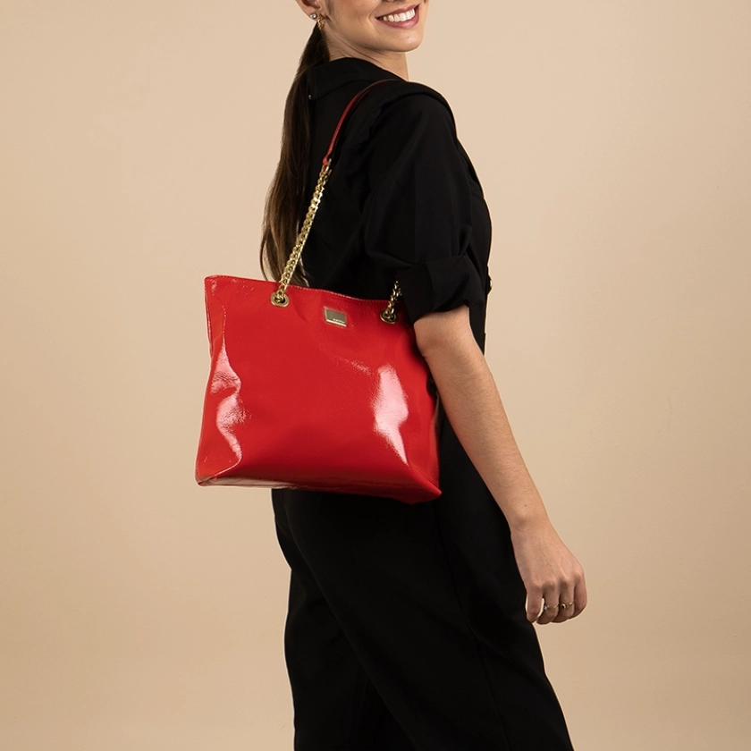 Na imagem, destaca-se uma linda bolsa feminina Rafitthy de ombro, confeccionada em verniz sintético vermelho, com um design sofisticado e acabamento impecável. O charme do modelo fica por conta da alça com detalhes de correntes douradas, que adiciona um toque de elegância. Além disso, as divisórias internas e bolsos práticos garantem organização e funcionalidade, tornando esta bolsa uma escolha ideal para quem busca estilo e praticidade.