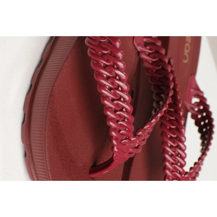 Na imagem temos o chinelo de dedo feminino dijean com correia de correntes trançada com acabamento interno acetinado e acabamento externo em verniz na cor telha bordo