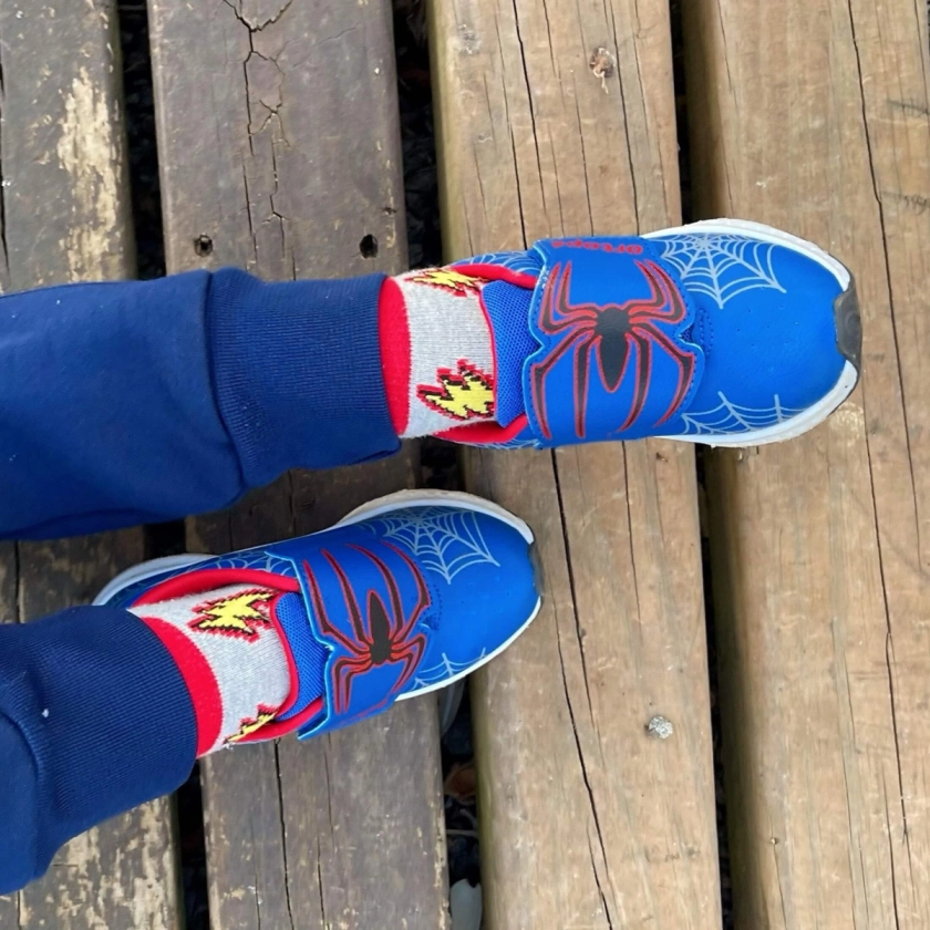 pé do menino calçando o tenis marinho com vermelho aranha